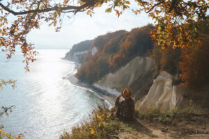 Woman sitting alone on the edge of the cliff and enjoying the view
