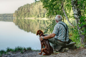 Early in the morning an old man sits with his young Irish Setter Pointer on the small bench by the lake and enjoys the silence of the beginning day.