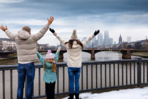 A happy tourist family enjoys the winter view of the skyline of Frankfurt, Germany, with snow